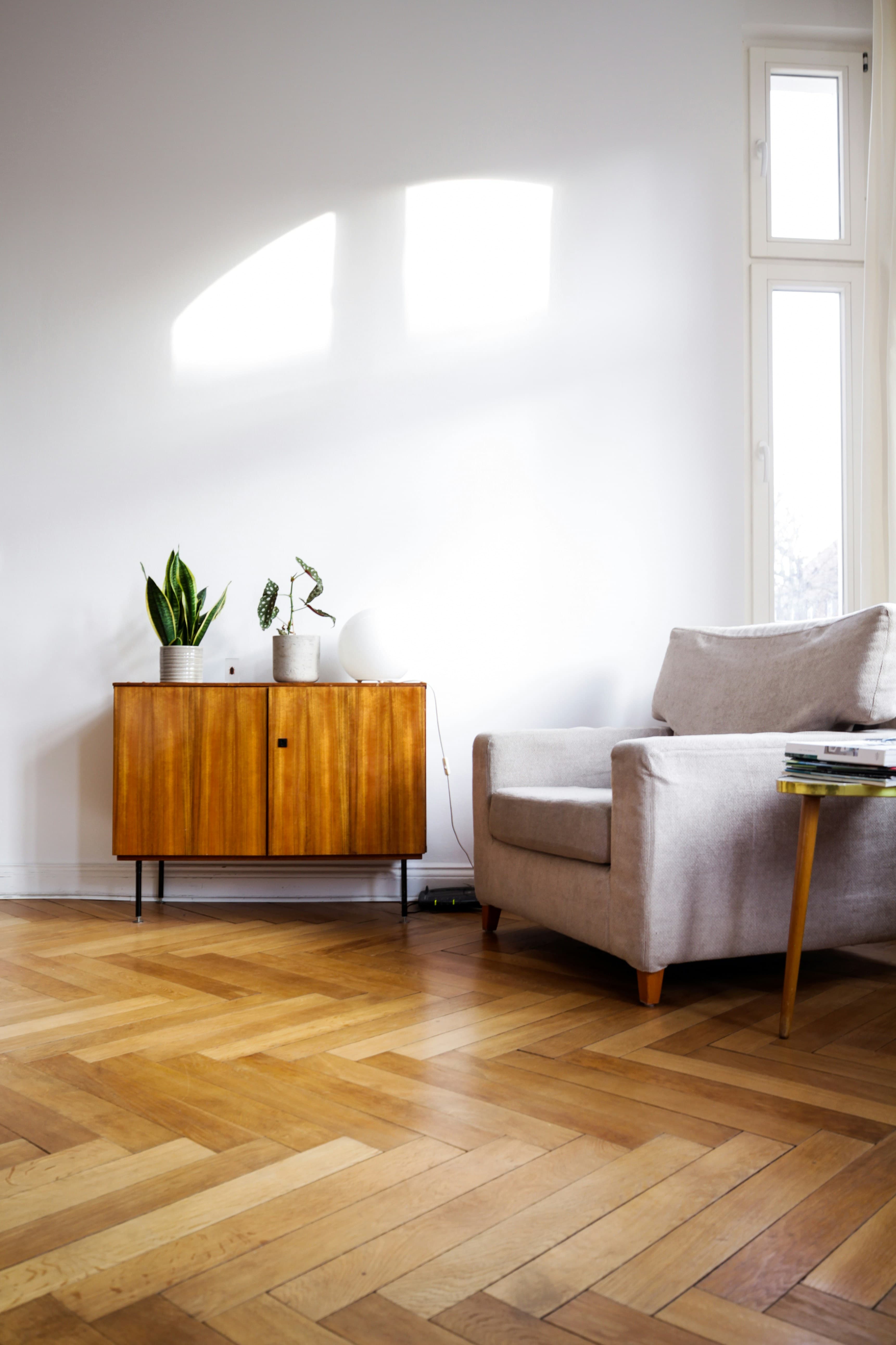 A modern, sunlit living room with wooden floors and a comfortable armchair.